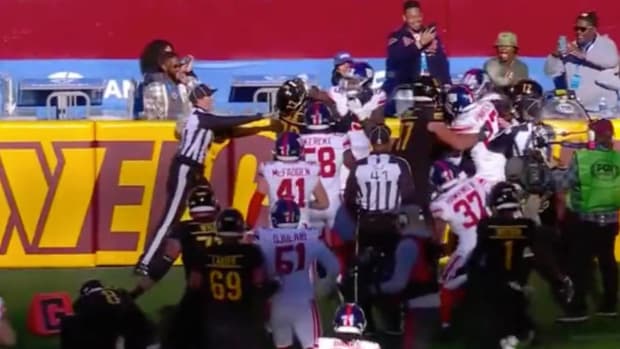 Giants and Commanders players engage on the sideline after a touchdown.